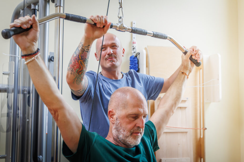 Therapeut betreut einen Patienten beim Training am Zugturm